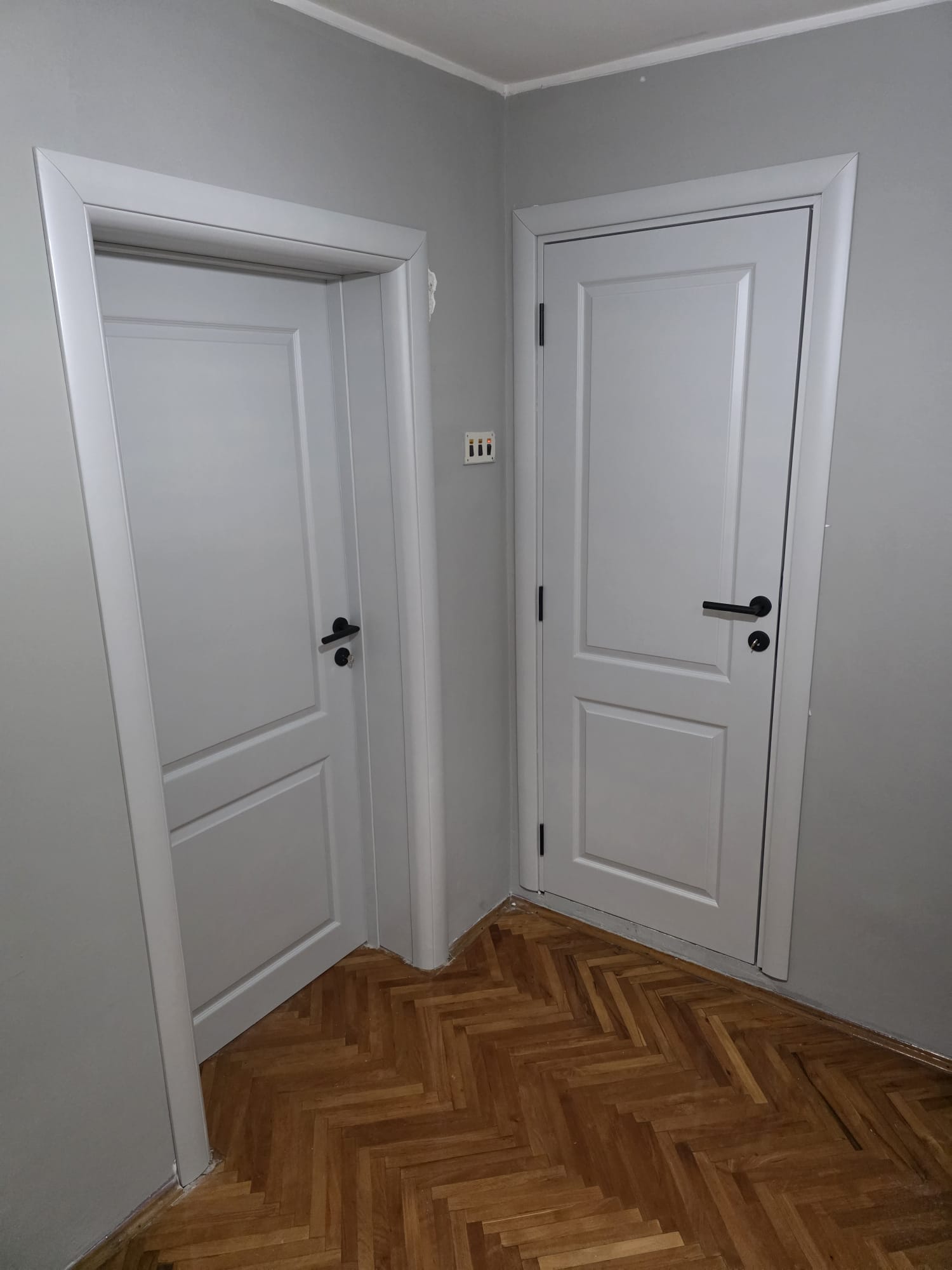 Dvoja klasična bela farbana vrata sa crnim kvakama