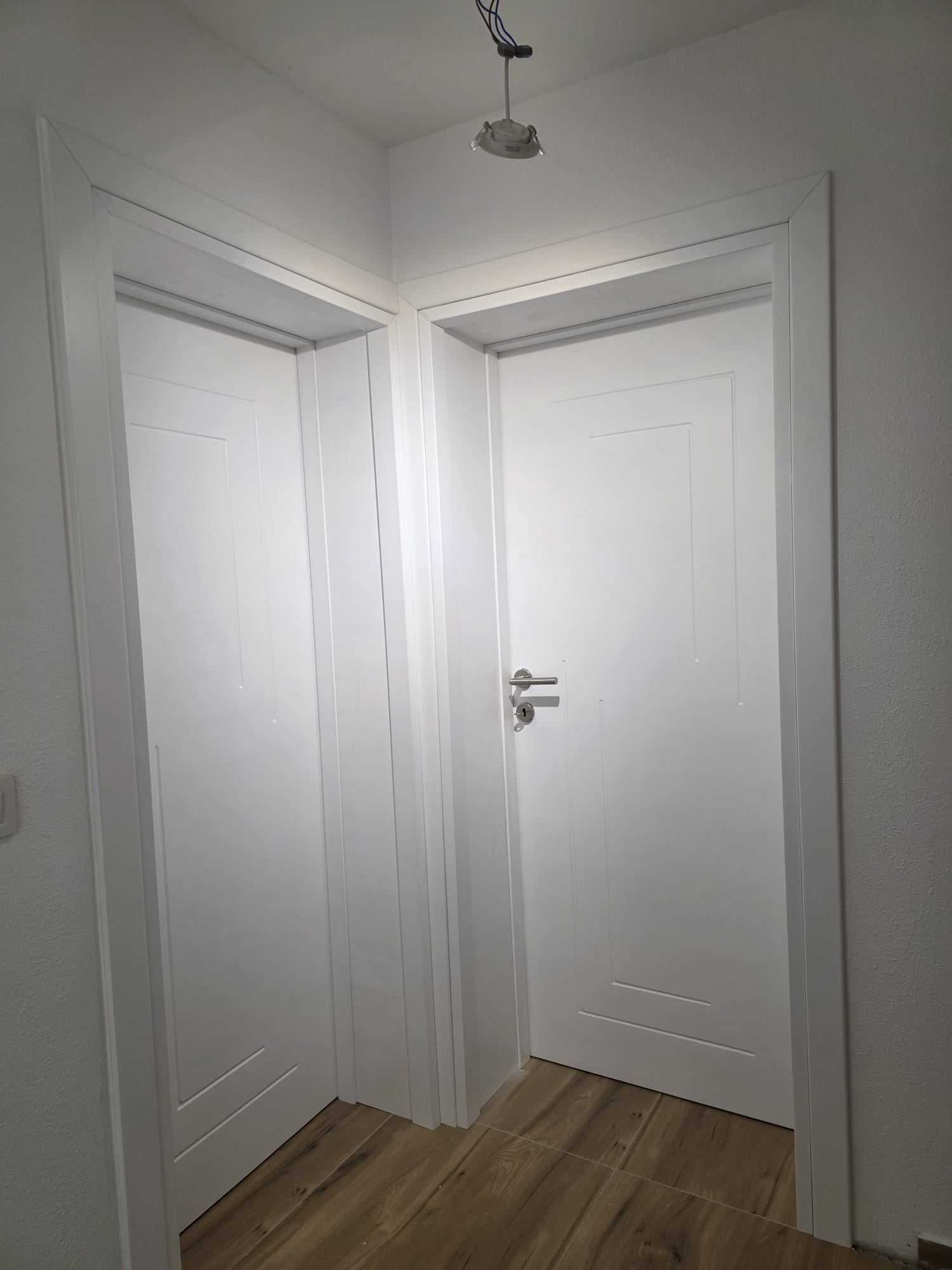 Dvoja bela farbana vrata sa geometrijskim dekorativnim linijama